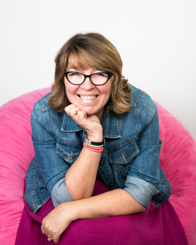 Dora Henderson, therapist and author, smiling in a pink beanbag chair